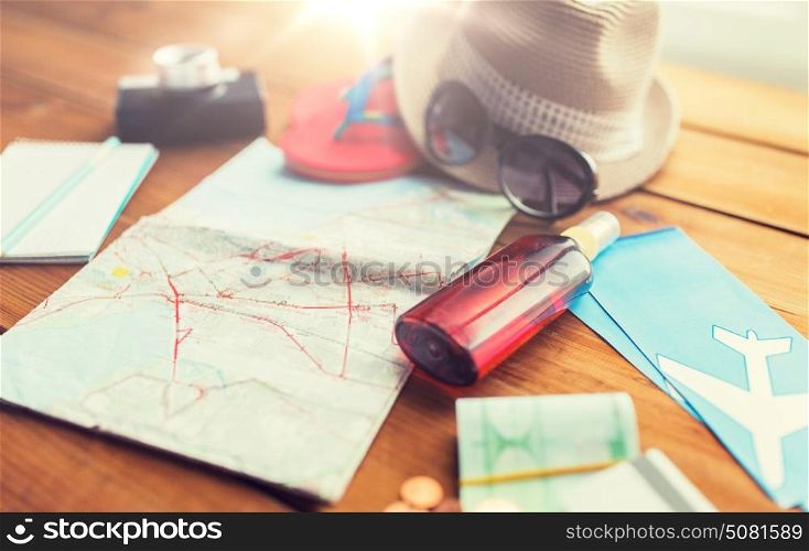 summer vacation, tourism and objects concept - close up of travel map, airplane tickets, money and personal accessories. close up of travel map, tickets, money and stuff