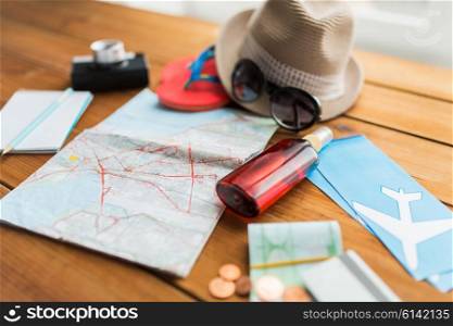 summer vacation, tourism and objects concept - close up of travel map, airplane tickets, money and personal accessories