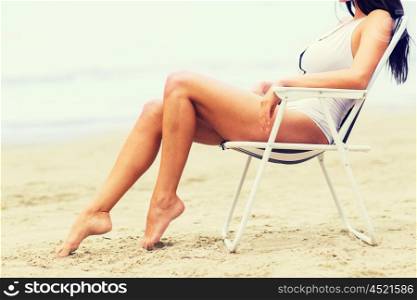 summer vacation, tourism, travel, holidays and people concept - close up of woman sunbathing in lounge on beach