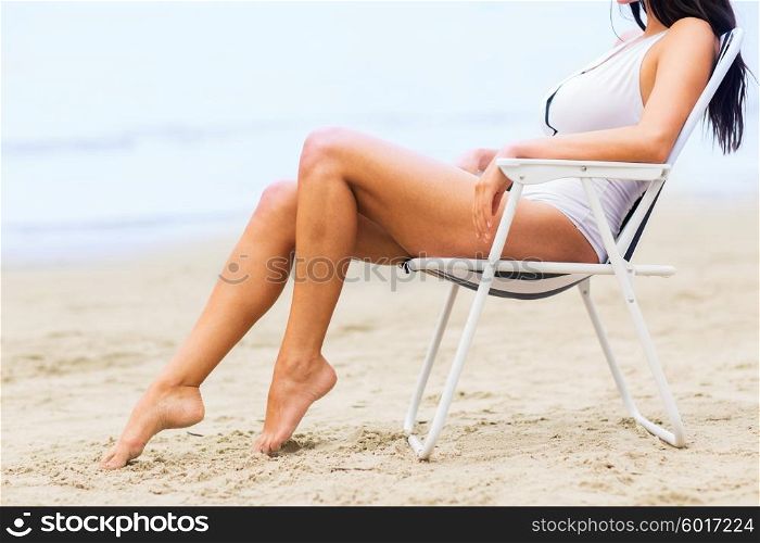 summer vacation, tourism, travel, holidays and people concept - close up of woman sunbathing in lounge on beach