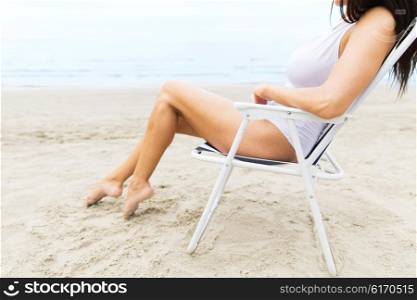 summer vacation, tourism, travel, holidays and people concept - close up of young woman sunbathing in lounge or folding chair on beach