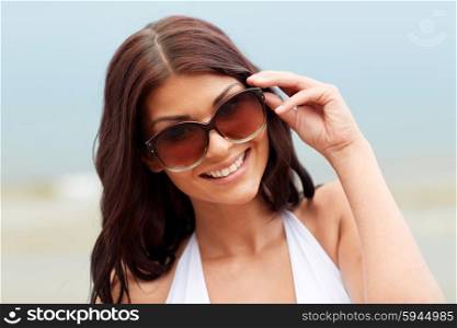 summer vacation, tourism, travel, holidays and people concept -face of smiling young woman with sunglasses on beach