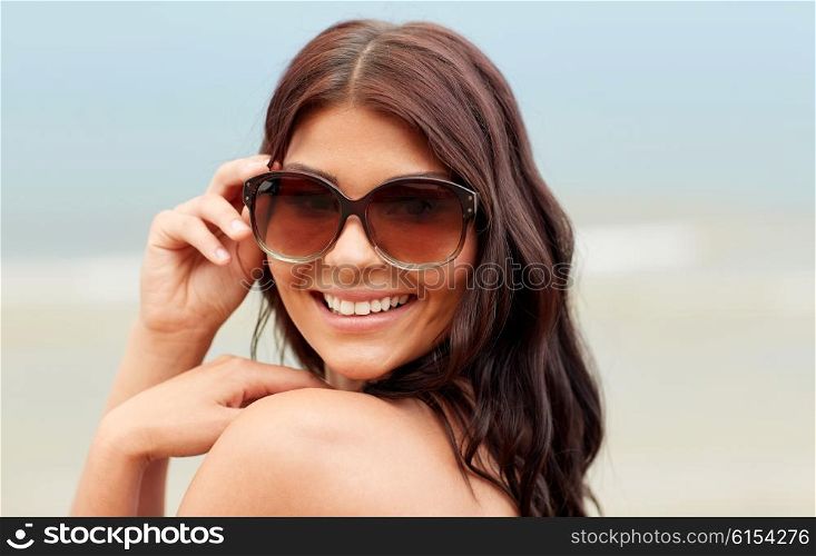 summer vacation, tourism, travel, holidays and people concept -face of smiling young woman with sunglasses on beach