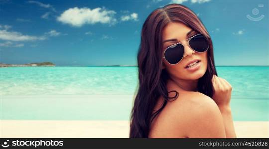 summer vacation, tourism, travel, holidays and people concept -face of young woman with sunglasses over tropical beach background