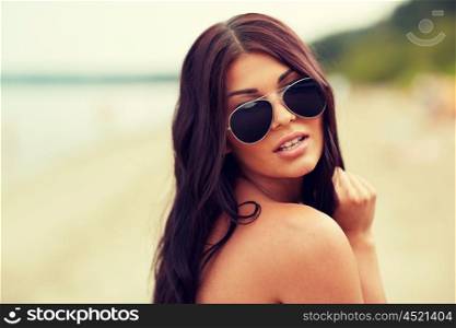 summer vacation, tourism, travel, holidays and people concept -face of young woman with sunglasses on beach