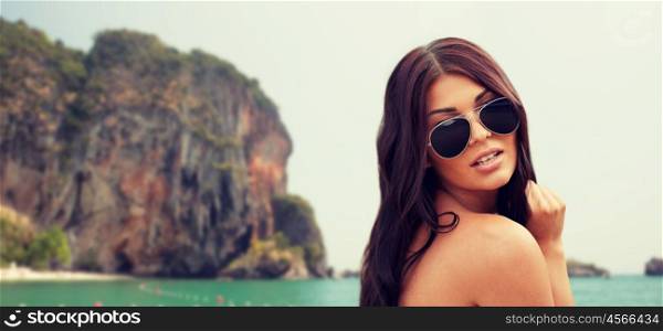 summer vacation, tourism, travel, holidays and people concept -face of young woman with sunglasses over rock on bali beach background