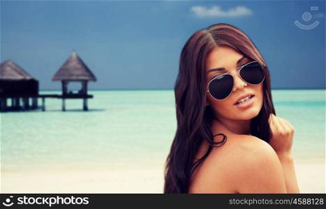 summer vacation, tourism, travel, holidays and people concept -face of young woman with sunglasses over bungalow on beach background