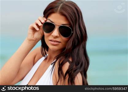 summer vacation, tourism, travel, holidays and people concept -face of young woman with sunglasses on beach