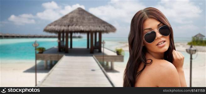 summer vacation, tourism, travel, holidays and people concept -face of young woman with sunglasses over bungalow on beach background
