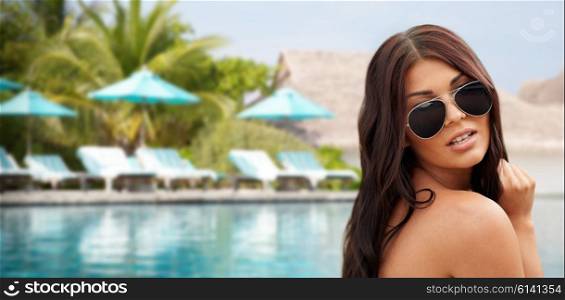 summer vacation, tourism, travel, holidays and people concept -face of young woman with sunglasses over beach and swimming pool background