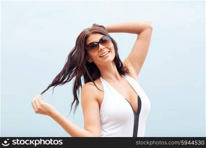 summer vacation, tourism, travel, holidays and people concept - smiling young woman in swimsuit with sunglasses on beach