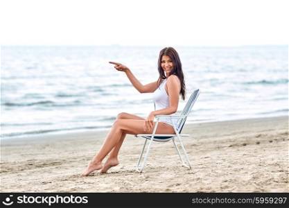 summer vacation, tourism, travel, holidays and people concept - smiling young woman sunbathing in lounge or folding chair on beach