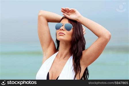 summer vacation, tourism, travel, holidays and people concept -young woman in swimsuit with sunglasses on beach
