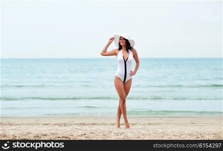 summer vacation, tourism, travel, holidays and people concept -young woman in swimsuit posing on beach