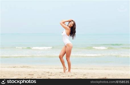 summer vacation, tourism, travel, holidays and people concept -young woman in swimsuit posing on beach