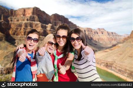 summer vacation, travel and tourism concept - beautiful teenage girls or young women showing thumbs up over rocks of grand canyon national park and colorado river background. teenage girls or young women showing thumbs up. teenage girls or young women showing thumbs up