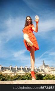 summer vacation, travel, fashion, emotion and people concept - shouting woman walking on city street with raising leg and hand