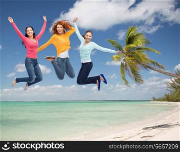summer vacation, travel, freedom, friendship and people concept - group of smiling young women jumping in air over tropical beach background