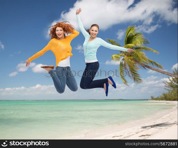 summer vacation, travel, freedom, friendship and people concept - smiling young women jumping in air over tropical beach background