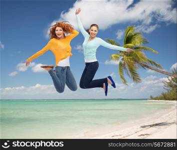 summer vacation, travel, freedom, friendship and people concept - smiling young women jumping in air over tropical beach background