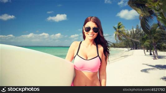 summer vacation, travel, surfing, water sport and people concept - young woman in swimsuit with surfboard over tropical beach with palms background