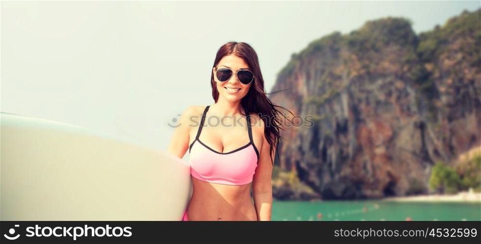 summer vacation, travel, surfing, water sport and people concept - young woman in swimsuit with surfboard over rock on bali beach background