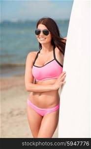 summer vacation, travel, surfing, water sport and people concept - young woman in swimsuit with surfboard on beach