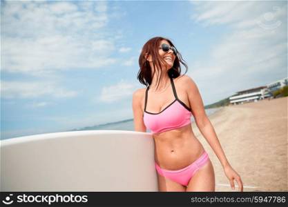 summer vacation, travel, surfing, water sport and people concept - young woman in swimsuit with surfboard walking on beach