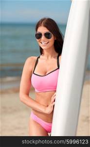 summer vacation, travel, surfing, water sport and people concept - young woman in swimsuit with surfboard on beach