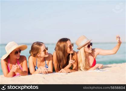 summer vacation, travel, technology and people concept - group of smiling women in sunglasses and hats making selfie with smartphone on beach