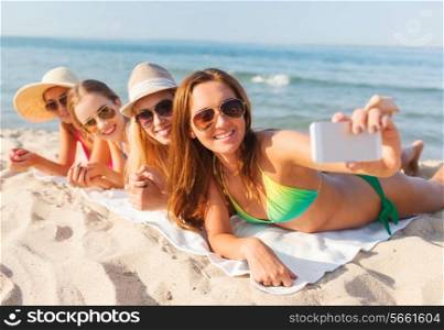 summer vacation, travel, technology and people concept - group of smiling women in sunglasses making selfie with smartphone on beach