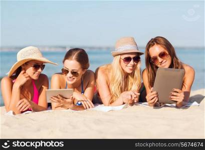summer vacation, travel, technology and people concept - group of smiling women in sunglasses with tablet pc computers lying on beach