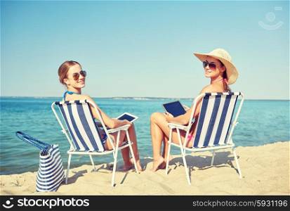 summer vacation, travel, technology and people concept - happy women with tablet pc computers sunbathing in lounges on beach
