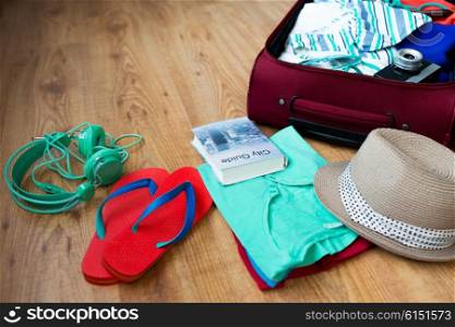 summer vacation, travel, tourism and objects concept - close up of travel bag with clothes and stuff