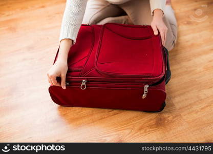 summer vacation, travel, tourism and objects concept - close up of woman packing and zipping travel bag for vacation