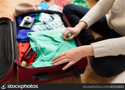 summer vacation, travel, tourism and objects concept - close up of woman packing travel bag for vacation