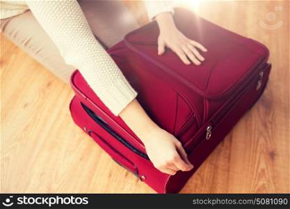 summer vacation, travel, tourism and objects concept - close up of woman packing and zipping travel bag for vacation. close up of woman packing travel bag for vacation