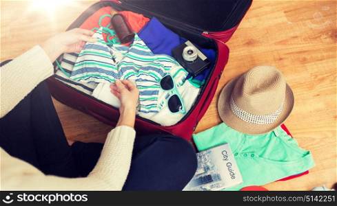 summer vacation, travel, tourism and objects concept - close up of woman packing travel bag for vacation. close up of woman packing travel bag for vacation