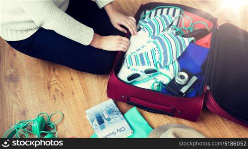summer vacation, travel, tourism and objects concept - close up of woman packing travel bag for vacation. close up of woman packing travel bag for vacation