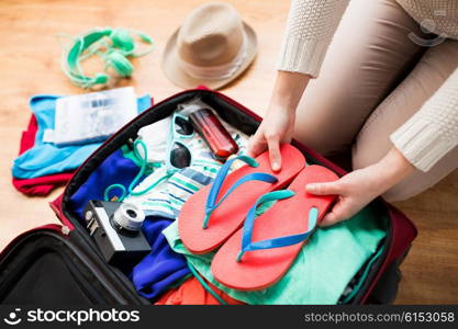 summer vacation, travel, tourism and objects concept - close up of woman packing travel bag for vacation