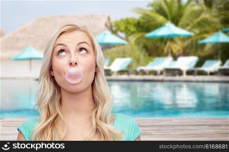 summer vacation, travel, tourism and people concept - happy young woman or teenage girl chewing gum over beach on touristic resort background