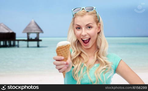 summer vacation, travel, tourism, junk food and people concept - young woman or teenage girl in sunglasses eating ice cream over beach on touristic resort background