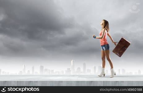 Summer vacation. Young pretty woman walking with suitcase in hand