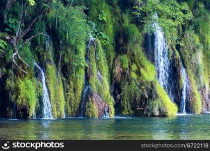 Summer view of beautiful small waterfalls and clear lake in front (Plitvice Lakes National Park, Croatia)