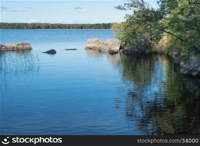 Summer view of the river. Nature background river Bay. Nature background river Bay with hanging trees and stone boulders in the water