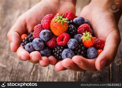 Summer wild berries in hands - raspberry, strawberry, blackberry and blueberry