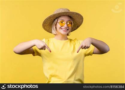 Summer woman pointing down to advertising area. Yellow background. Young lady asking to click to subscribe below. Copy space for your commercial idea, promotional content. High quality photo. Summer woman pointing down to advertising area. Yellow background. Young lady asking to click to subscribe below. Copy space for your commercial idea, promotional content.