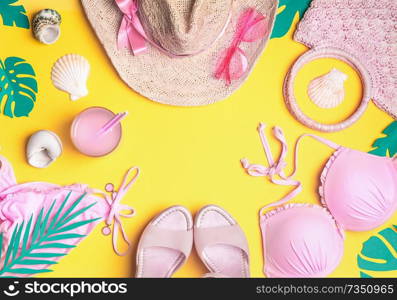 Summer yellow background with pink bikini, straw hat, sunglasses, sandals with cocktail , seashells , tropical palm leaves. Summer female fashion outfit. Girls beach accessories. Top view, frame