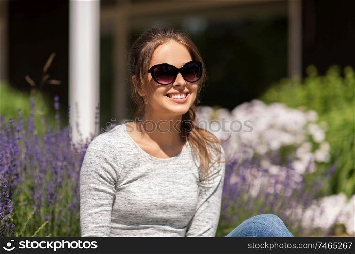 summertime, leisure and people concept - happy young woman in sunglasses at summer garden. happy young woman in sunglasses at summer garden