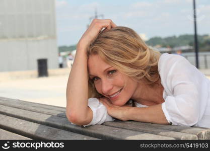 Summery woman leaning on a bench